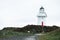 A man walking at Waipapa point, the lighthouse, ocean and cloudy. I