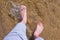 Man is walking on water shallow on sand bottom legs close up summer vacation.