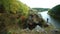 A man walks along a rock on a river.