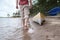 A man walks barefoot on the water of the lake to his kayak, which is parked on a sandy beach. Lifestyle.