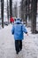 A man walks down an alley in the park in winter. Rear view