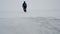 A man walks on a frozen surface of a lake