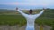 A man walks at a height in the vineyards near the mountains, stands with his back in the frame, raising his hands up.