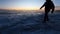 A man walks on the ice on the shore of the lake during the sunrise. Silhouette of a man