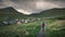 Man walks on path in front of the village of Gjogv on Eysturoy, Faroe Islands