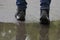 A man walks through puddles. Rainy day. Wet asphalt. Boots