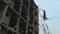 A man walks on a rope at a height on an abandoned construction site.