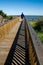 Man walks toward ocean on boardwalk