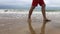 Man walks by wet sea beach with waves from left to right