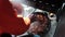 A Man in warm clothing tosses water on wood chips for a smoker cooking turkey