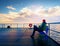 Man in warm jacket and baseball cap sit on mole bench and enjoy morning at sea.