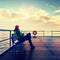 Man in warm jacket and baseball cap sit on mole bench and enjoy morning at sea.