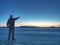 Man in warm suit gesture to morning horizon. Hiker stay on ice