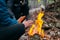 Man warms his hands on fire. Burning wood at evening in the forest. Campfire at touristic camp at nature. Barbeque and