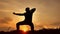 Man warrior monk practicing silhouette karate kung Fu on the grassy horizon at sunset. Karate kick leg. Art of self