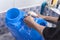 A man washes a blue 5 gallon HPDE water container with soap at the sink. Cleaning jugs at a water refilling station