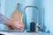 A man washes fruit in a sink in a kitchen with blue walls. Against the background of fruits