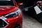 A man washes the headlights of a red car with a spray.