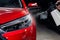 A man washes the headlights of a red car with a spray.