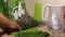 A man washes under the tap in the kitchen large leaves beet tops. Clean leaves are placed to the right of the sink