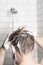 A man washing her hair with shampoo in the shower room.