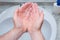 A Man is washing his hands with soap in bathroom.