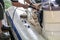 Man washing white inflatable boat with brush and pressure water system at garage. Ship service and seasonal maintenance concept