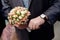 Man with watch hands a flower bouquet