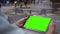 A man watches a green screen tablet in downtown business area near water features