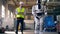 Man watches a robot walk in a factory room.