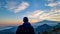 Man watching beautiful sunset behind volcano Mount Etna near Castelmola, Taormina, Sicily. Clouds with vibrant red orange colors