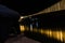 Man watching iron suspension bridge illuminated with ferry lights with water reflection