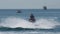 A man on a water motorcycle sails on the sea against the backdrop of a wave boat