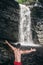 Man at waterfall enjoy the view and travel with arms raised.