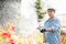 Man watering plants outside greenhouse