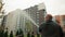 A man waters the lawn and newly planted trees near new buildings from a hose. Landscaping and care of the surrounding