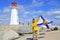 Man waving Nova Scotia flag in front the lighthouse of Peggy`s Cove