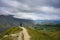 A man wear black stands on a hill to see a panoramic view at the Arrow Junction Lookout Point during the summer in Otago