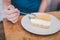 Man wear blue t-shirt sitting in coffee shop eating lemon cheesecake in white plate with folk