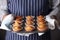 Man Wearing Apron Holding Tray Of Freshly Baked Cupcakes