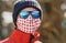 Man wearing beanie hat, blue shiny sunglasses and white red cotton home made nose mouth face virus mask, closeup detail portrait,