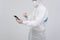 Man wearing biological protective uniform suit clothing, mask, gloves spraying sanitizer on smartphone for sanitizing virus