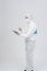 Man wearing biological protective uniform suit clothing, mask, gloves spraying sanitizer on tablet for sanitizing virus bacteria