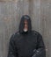 Man Wearing a Black Hooded Cape with Snow Falling Down