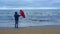 Man wearing blue jacket opens big red umbrella on seashore