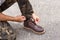 Man wearing cargo pants and tying the laces on leather shoes boot