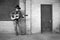 Man wearing cowboy hat and blue jeans playing acoustic guitar on factory loading dock