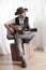 Man wearing cowboy leather hat and cowboy boots playing acoustic guitar