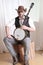 Man wearing cowboy leather hat and sunglasses holding banjo