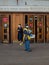 A man wearing a face mask and uniform distributes newspapers to people exiting the doors of a subway station